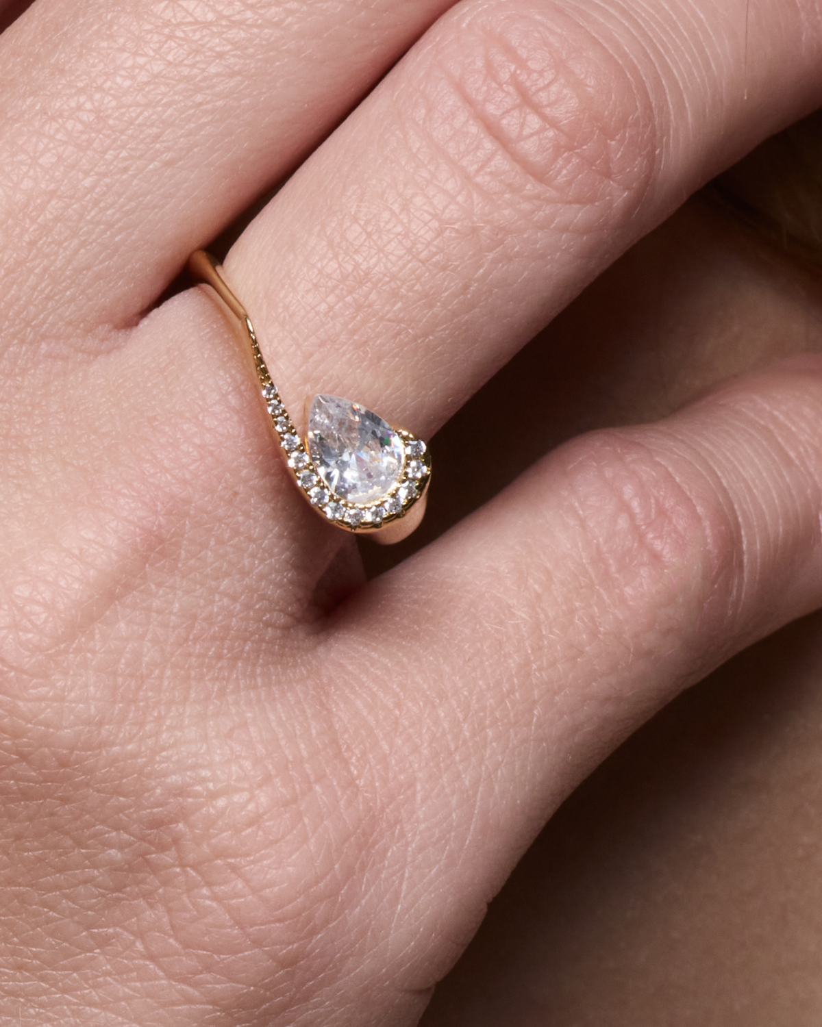 Bague « Pear Glow » en argent 925 rhodié, pierre centrale en zirconium taille poire entourée d’un délicat pavage de zirconiums, anneau légèrement torsadé à la finition polie brillante.