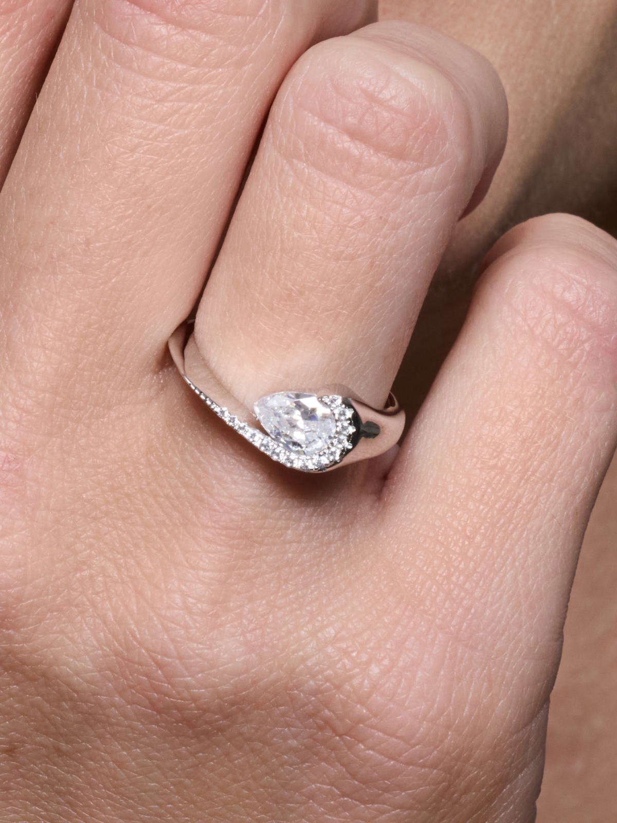 Bague Pear Glow blanche en argent 925 rhodié avec pierre centrale en zirconium taille poire entourée d’un délicat pavage de zirconiums, design fluide et asymétrique qui épouse le doigt pour un éclat subtil et raffiné.