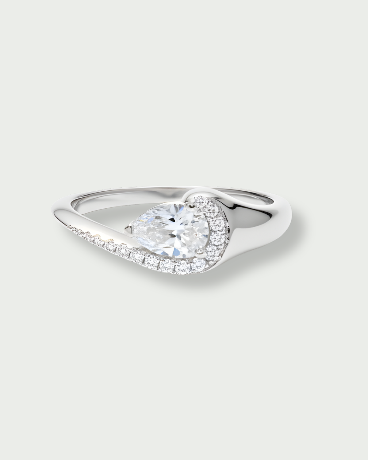 Bague Pear Glow blanche en argent 925 rhodié avec pierre centrale en zirconium taille poire entourée d’un délicat pavage de zirconiums, design fluide et asymétrique qui épouse le doigt pour un éclat subtil et raffiné.