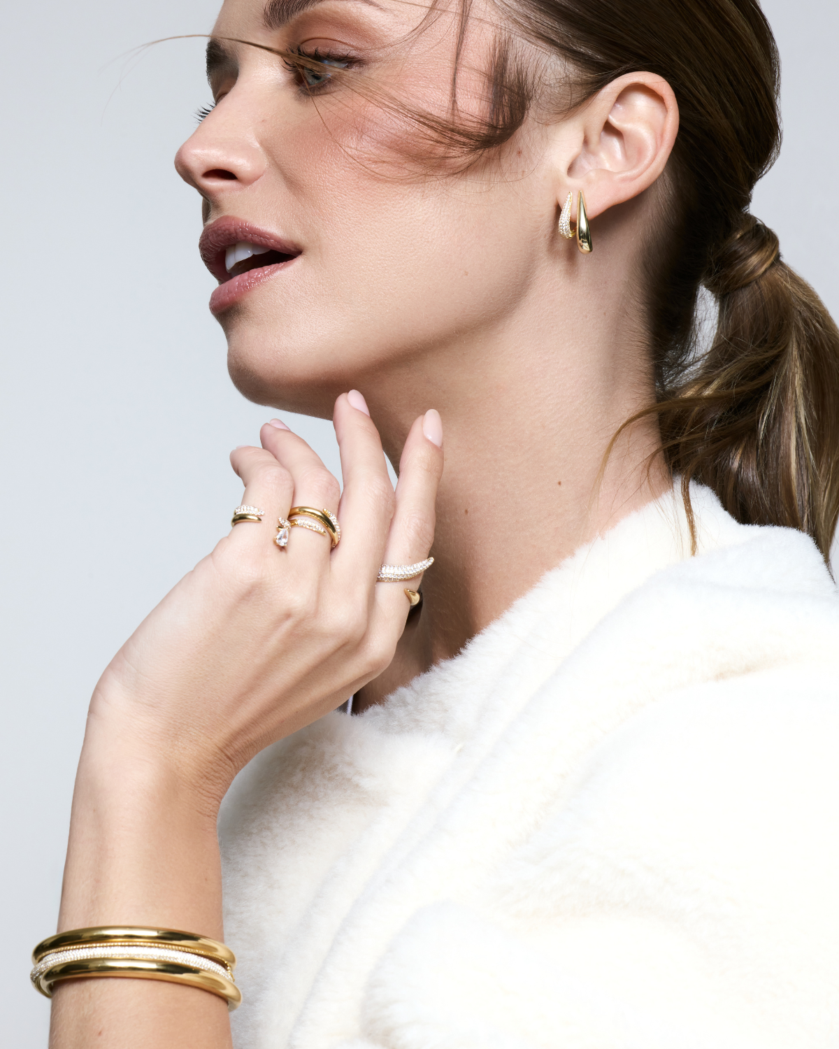 Boules d’oreilles Shape dorées en argent 925 plaqué or 18 carats avec pavage de zirconiums, design créole graphique et moderne qui enveloppe délicatement le lobe pour une silhouette sculpturale et lumineuse.