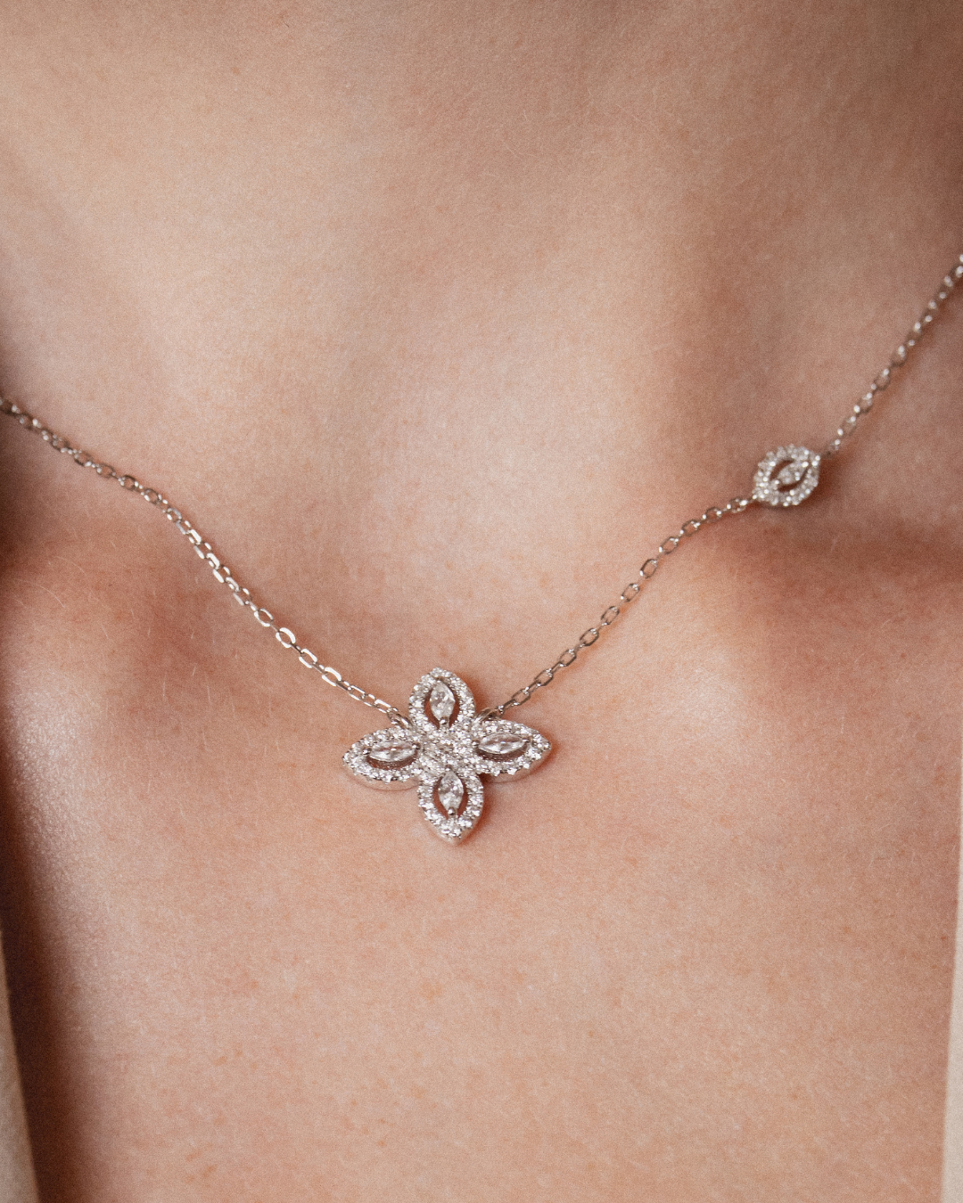Collier « Fleur de Vie » en argent 925 rhodié, motif floral orné d’un zirconium central et de quatre pierres taille marquise, chaîne réglable 38 + 8 cm, finition polie brillante.