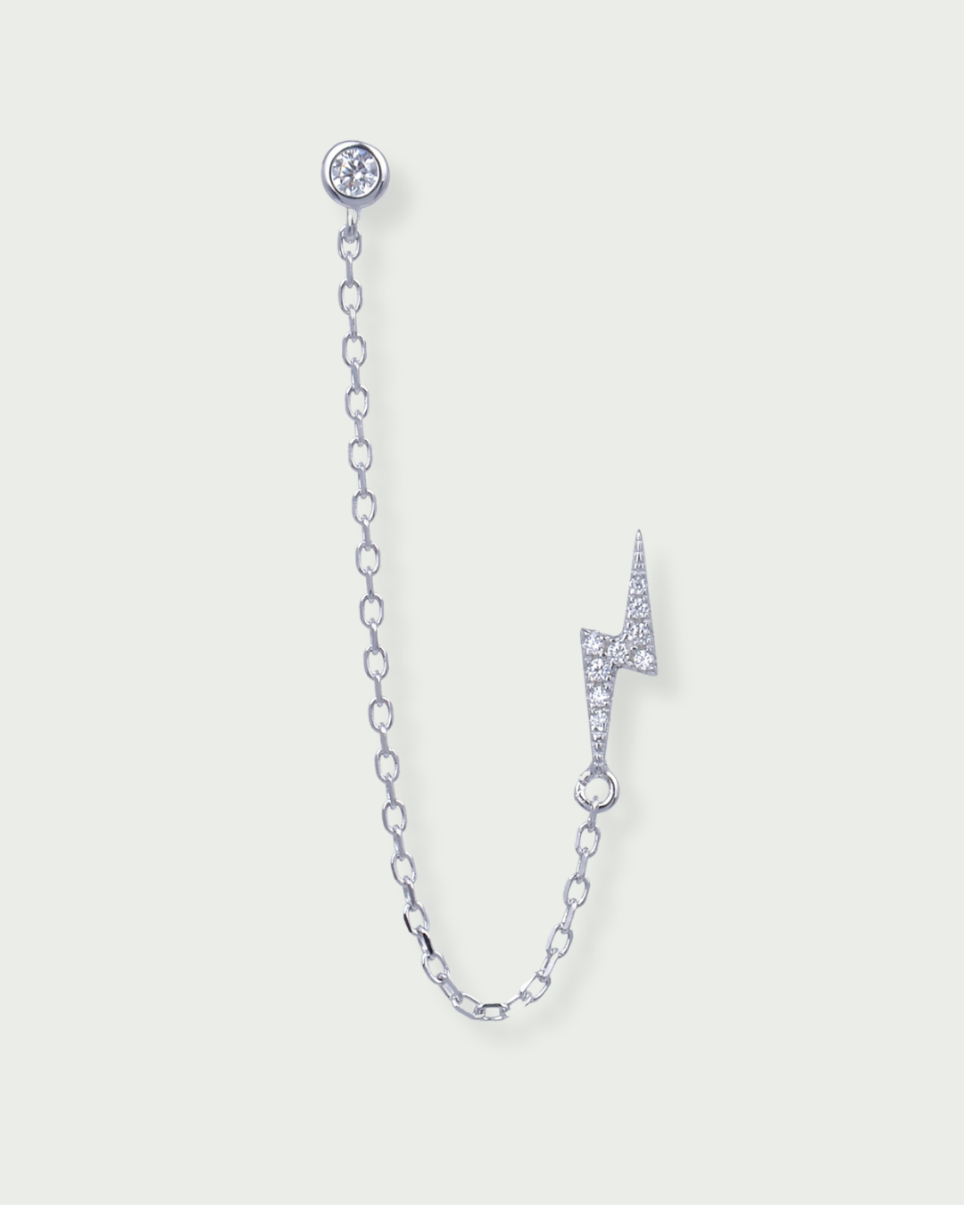 Monoboucle en argent 925 rhodié, puce serti clos relié par une chaîne fine à une puce éclair pavée, finition polie brillante.