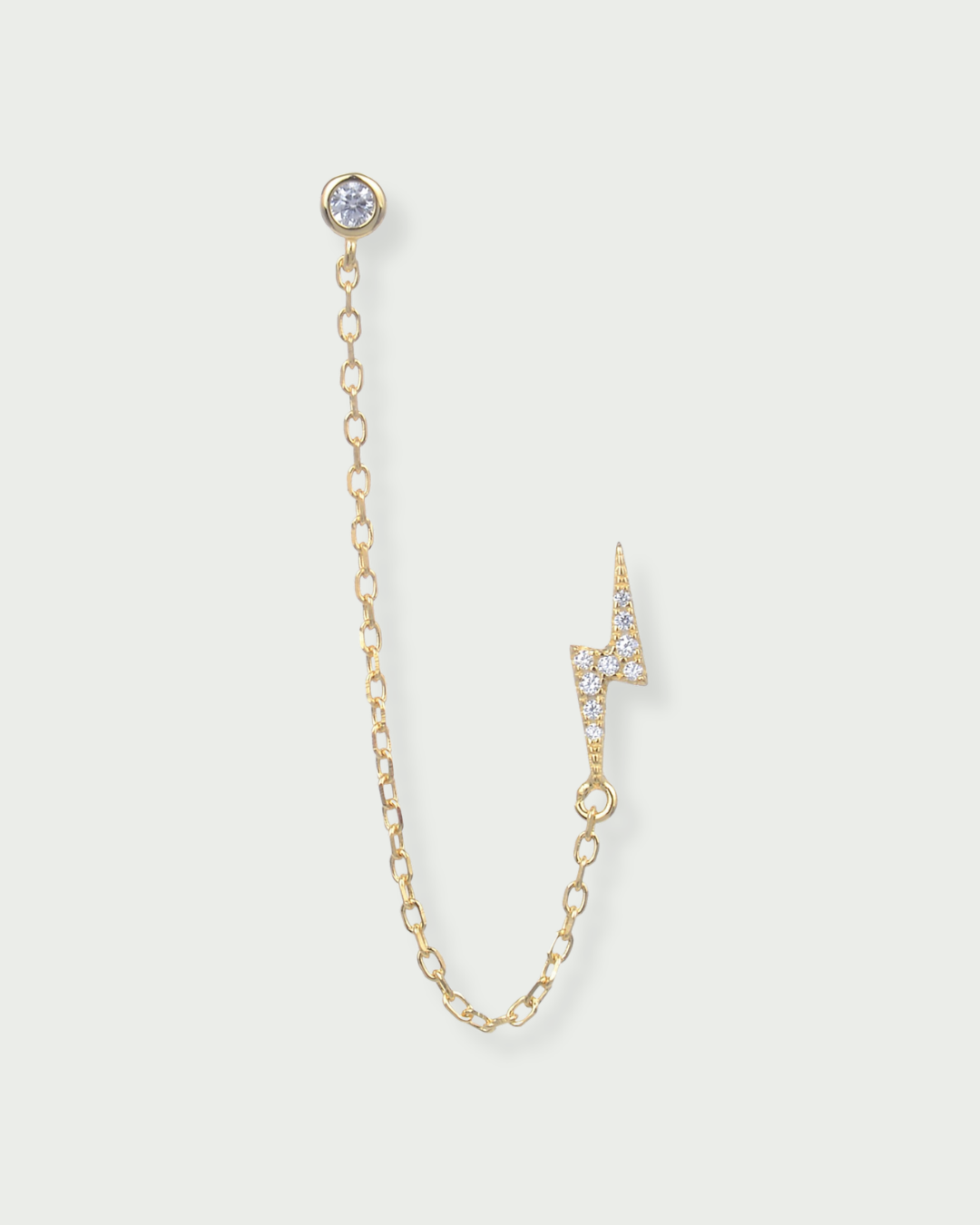 Monoboucle en argent 925 doré à l’or jaune 18 carats, puce serti clos relié par une chaîne fine à une puce éclair pavée, finition polie brillante.