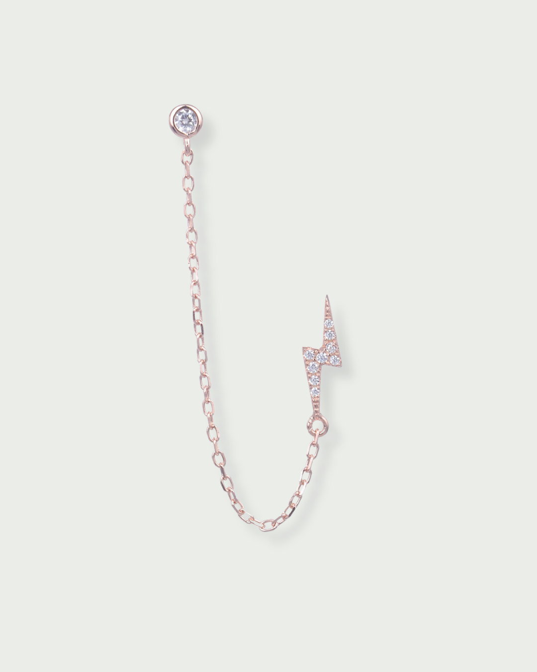 Monoboucle en argent 925 doré à l’or rose 18 carats, puce serti clos relié par une chaîne fine à une puce éclair pavée, finition polie brillante.