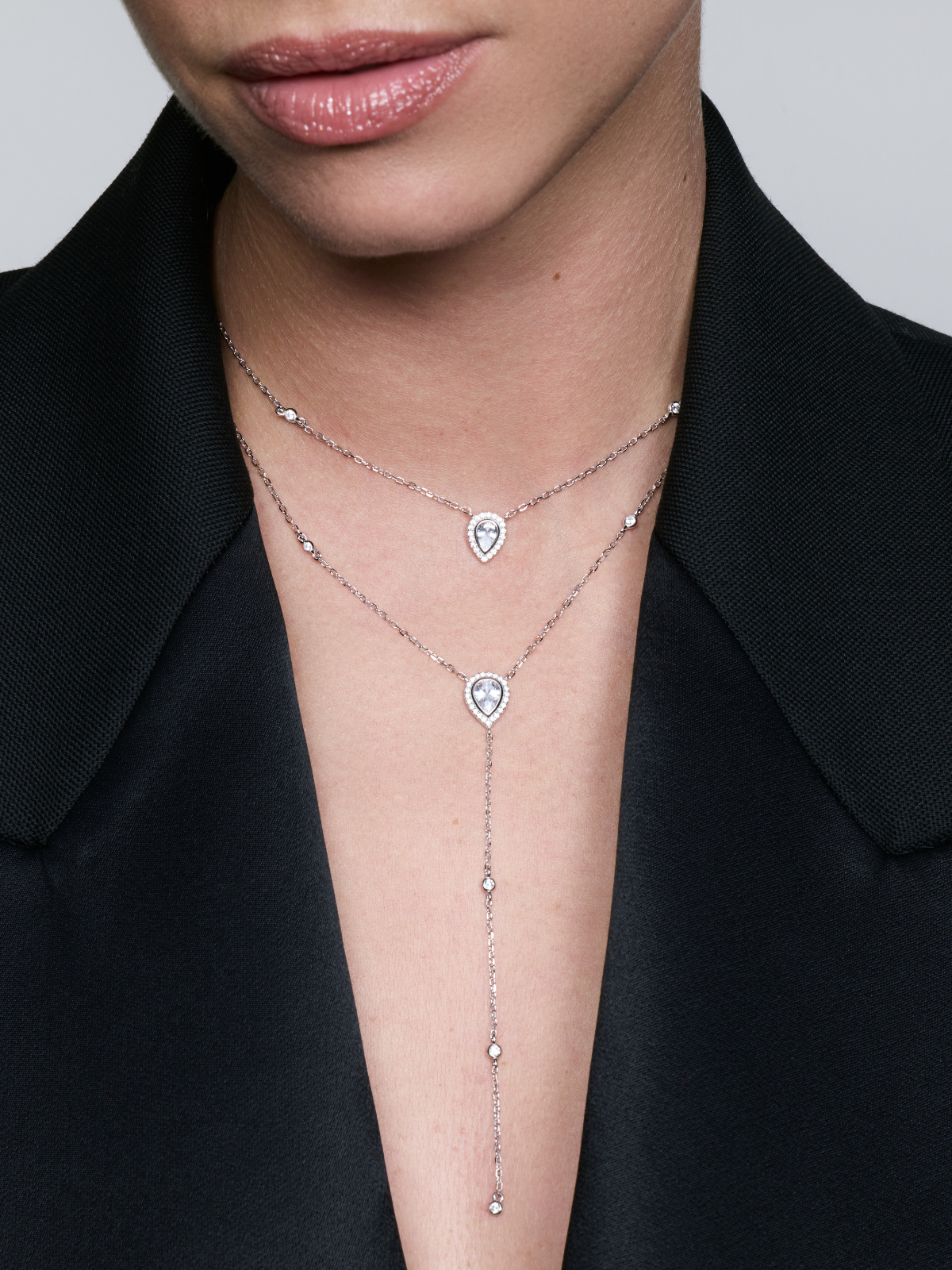 Sautoir double Signature blanc en argent 925 rhodié avec deux chaînes délicates ornées de pendentifs en zirconium taille poire, silhouette en Y élégante et lumineuse qui met en valeur le décolleté avec finesse et sophistication.