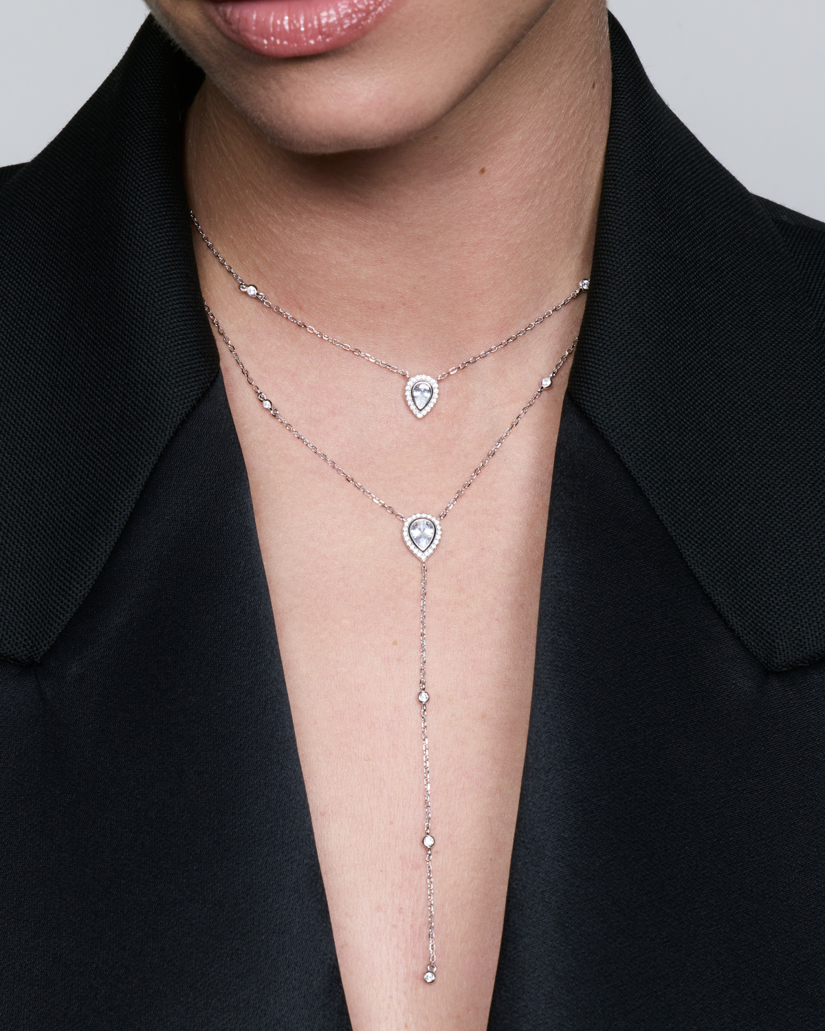Sautoir double Signature blanc en argent 925 rhodié avec deux chaînes délicates ornées de pendentifs en zirconium taille poire, silhouette en Y élégante et lumineuse qui met en valeur le décolleté avec finesse et sophistication.