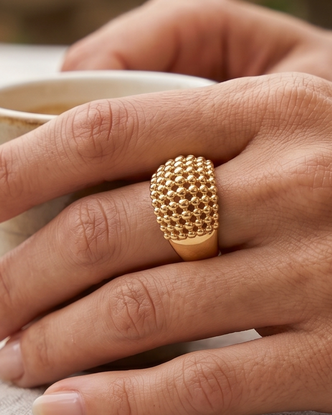 Bague Perle Maxi en argent 925 doré à l’or jaune 18 carats, ornée d’un large motif bombé composé de perles métalliques de différentes tailles.