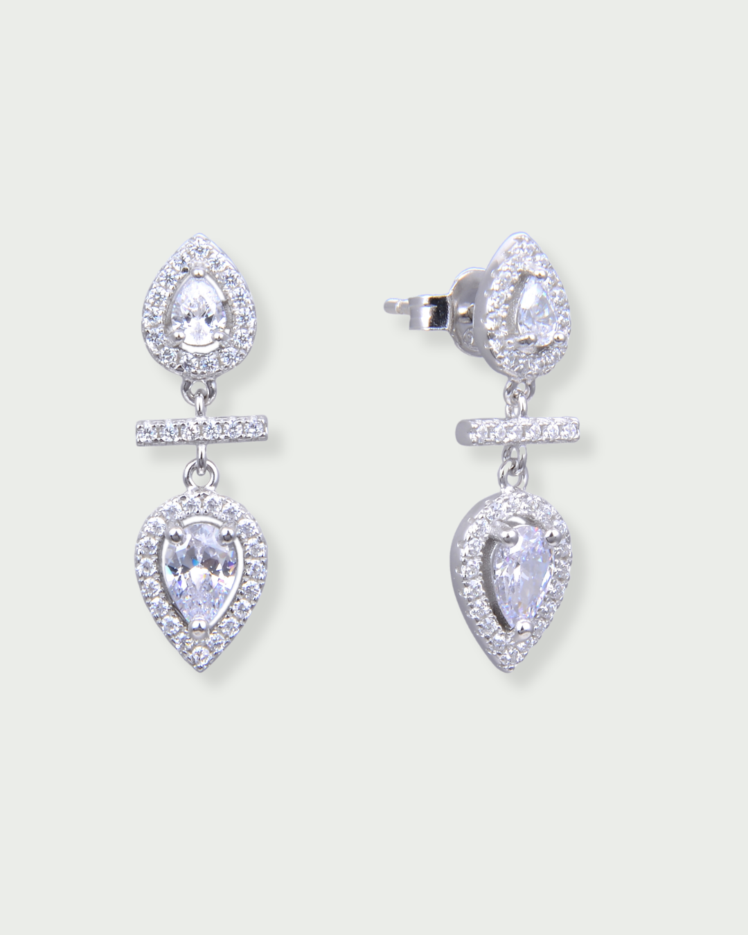 Boucles d’oreilles « Opposite Infini Poire » en argent 925 rhodié, deux zircons blancs taille poire montés en symétrie miroir, séparés par une petite barre sertie, finition polie brillante.