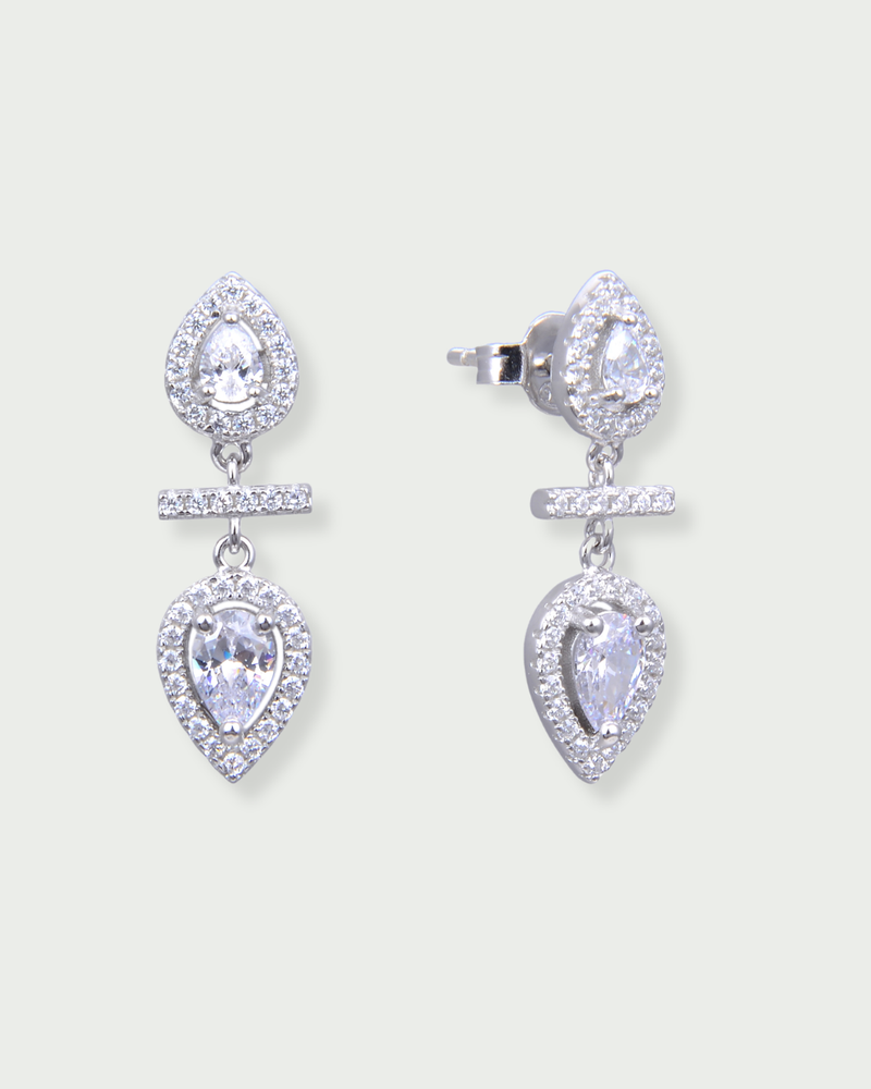 Boucles d’oreilles « Opposite Infini Poire » en argent 925 rhodié, deux zircons blancs taille poire montés en symétrie miroir, séparés par une petite barre sertie, finition polie brillante.