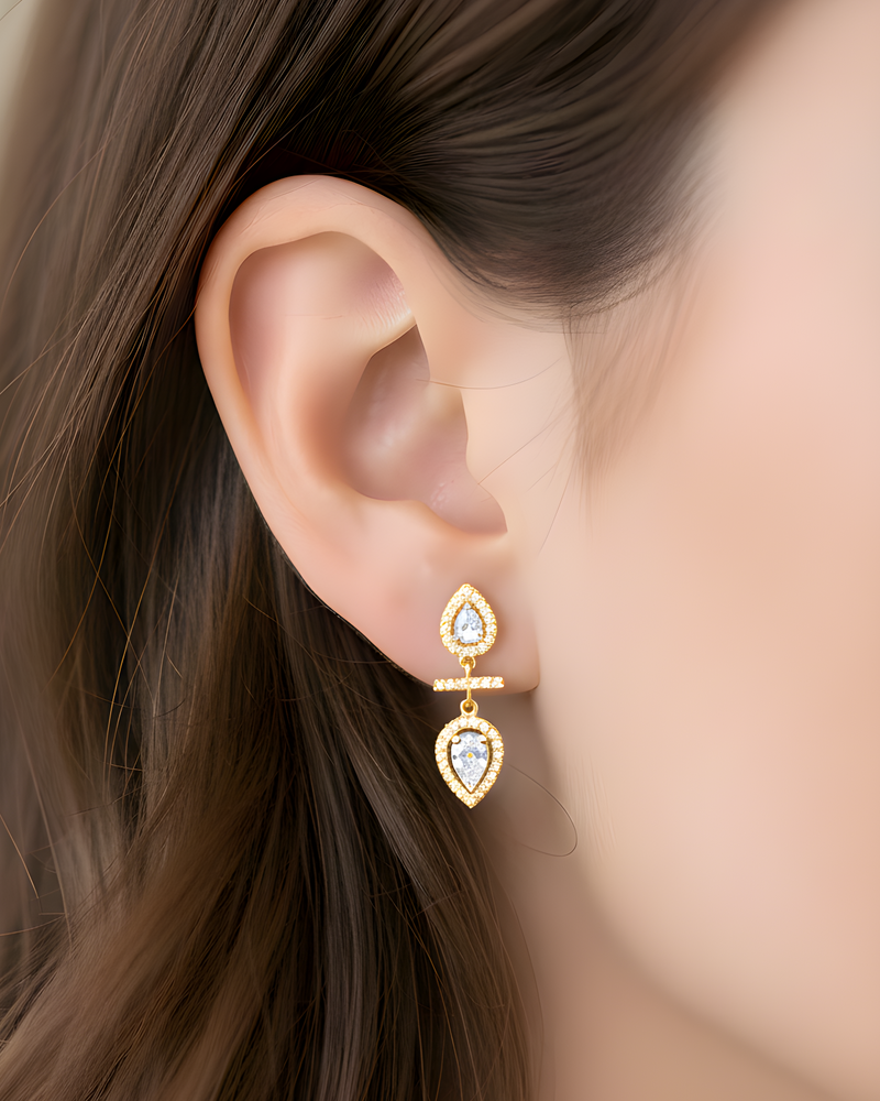 Boucles d’oreilles « Opposite Infini Poire » en argent 925 doré à l’or jaune 18 carats, deux zircons blancs taille poire montés en symétrie miroir séparés par une petite barre sertie, finition polie brillante.