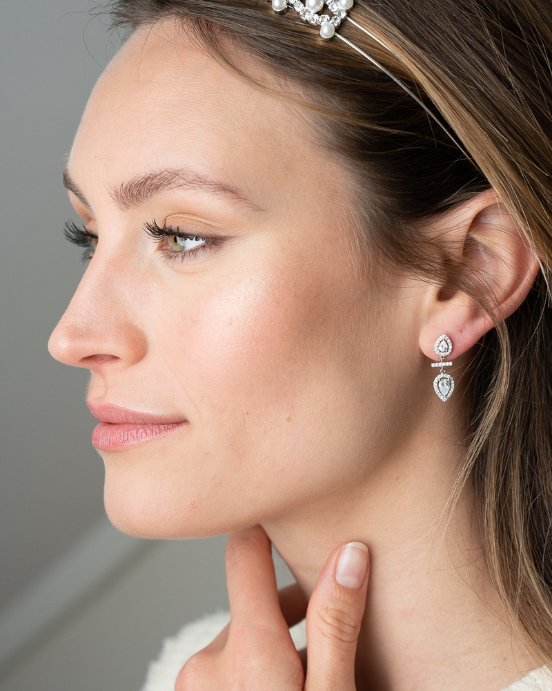 Boucles d’oreilles « Opposite Infini Poire » en argent 925 rhodié, deux zircons blancs taille poire montés en symétrie miroir, séparés par une petite barre sertie, finition polie brillante.
