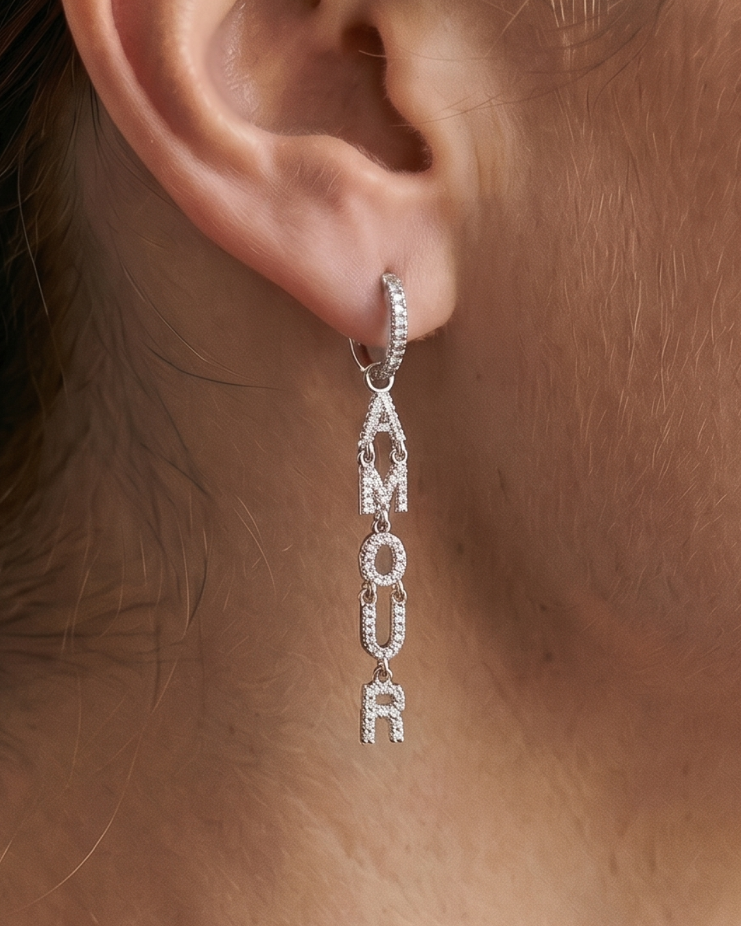 Boucles d’oreilles pendantes « Amour » en argent 925 rhodié, lettres serties de zirconiums formant le mot AMOUR suspendues à un anneau, finition polie brillante.