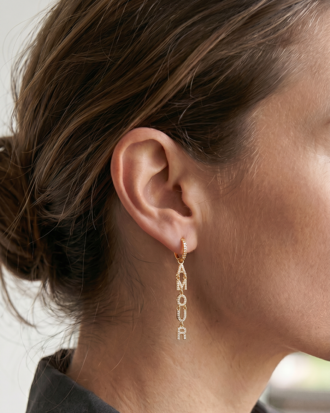 Boucles d’oreilles pendantes « Amour » en argent 925 doré à l’or fin 18 carats, lettres serties de zirconiums formant le mot AMOUR suspendues à un anneau, finition polie brillante.