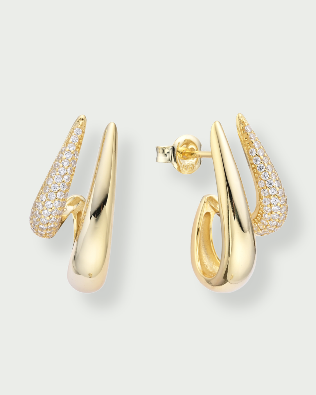 Boules d’oreilles Shape dorées en argent 925 plaqué or 18 carats avec pavage de zirconiums, design créole graphique et moderne qui enveloppe délicatement le lobe pour une silhouette sculpturale et lumineuse.