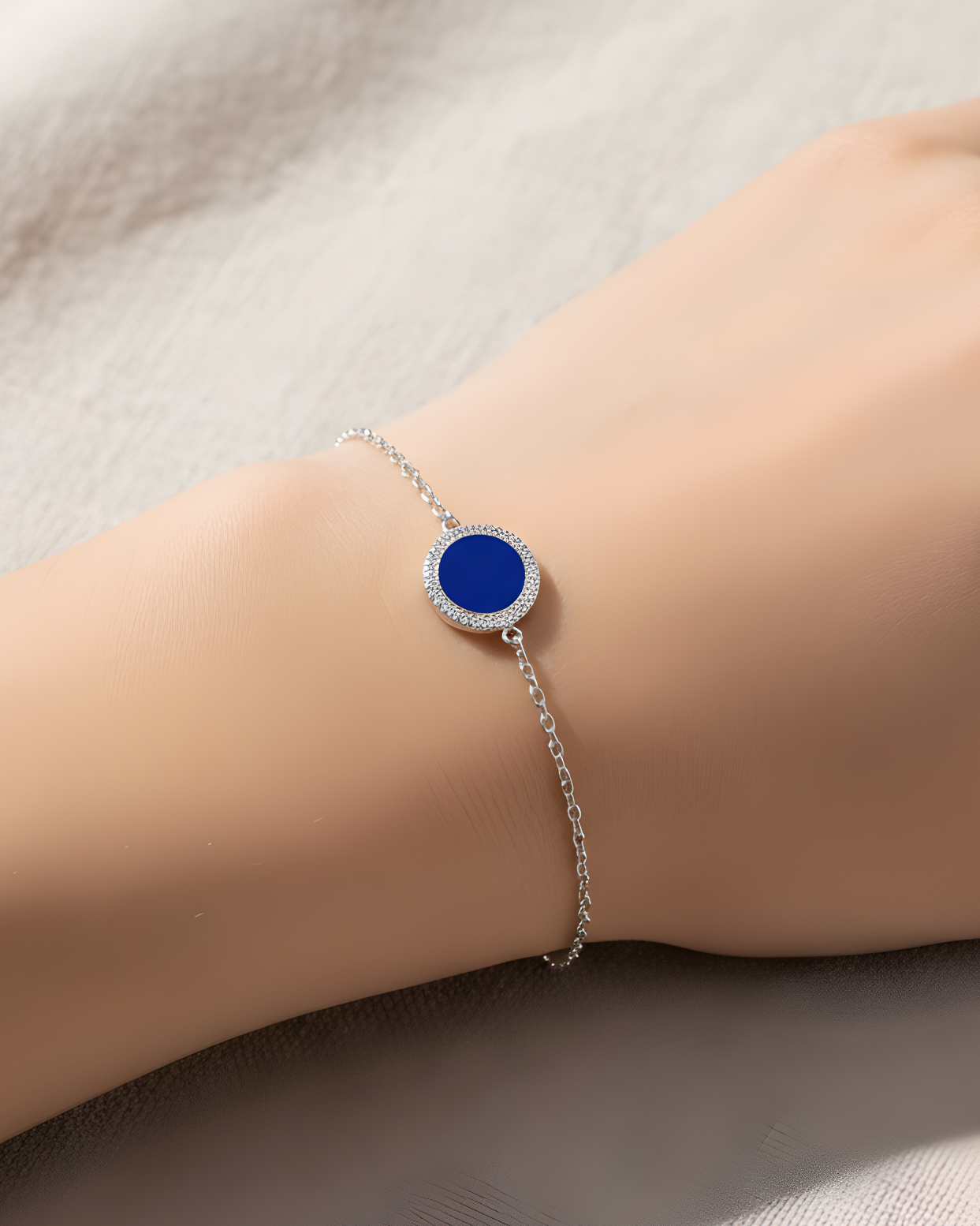 Bracelet en argent 925 rhodié, orné d’une petite médaille ronde sertie d’une pierre lapis-lazuli, finition polie brillante.