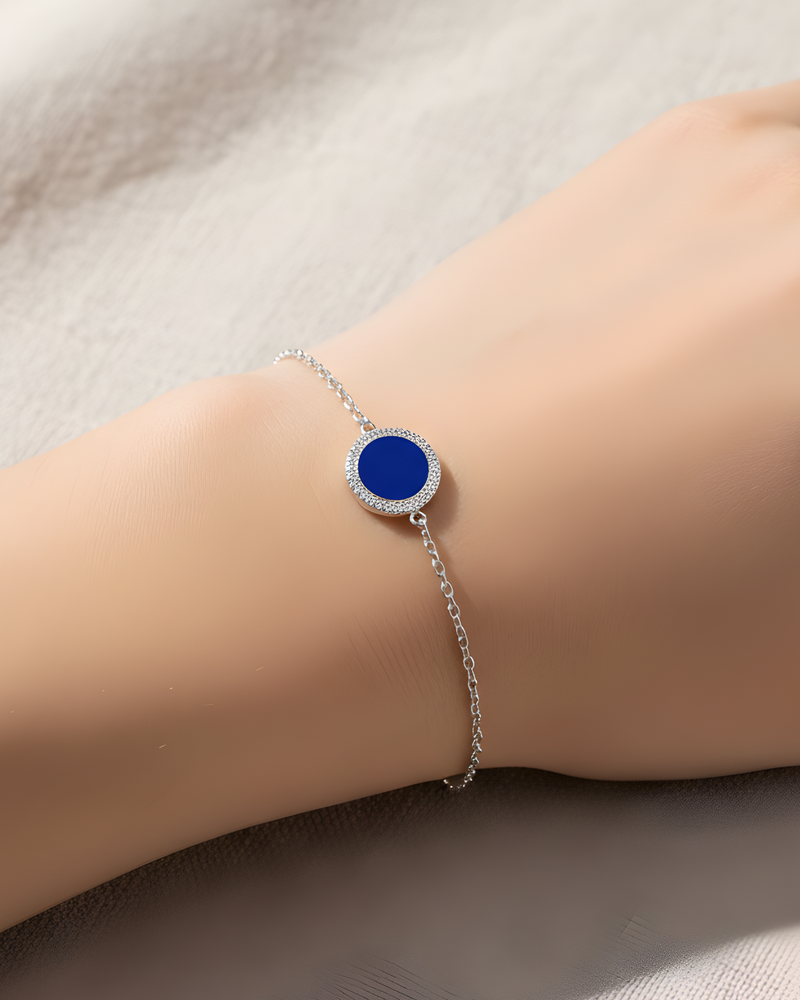 Bracelet en argent 925 rhodié, orné d’une petite médaille ronde sertie d’une pierre lapis-lazuli, finition polie brillante.