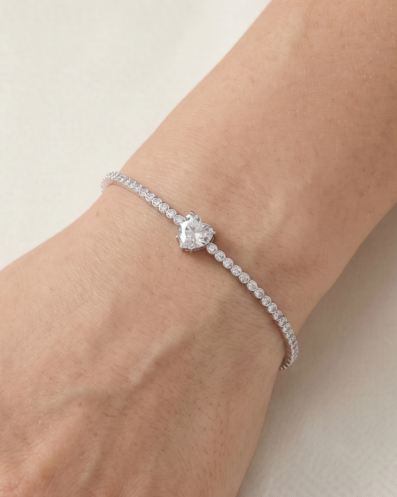 Bracelet Tennis Cœur Blanc en argent 925, composé d’une rivière de zirconiums blancs et orné d’un zirconium central en forme de cœur.