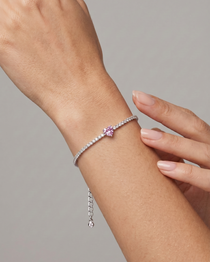 Bracelet Tennis Cœur Rose en argent 925, composé d’une rivière de zirconiums blancs et orné d’un zirconium rose central en forme de cœur.