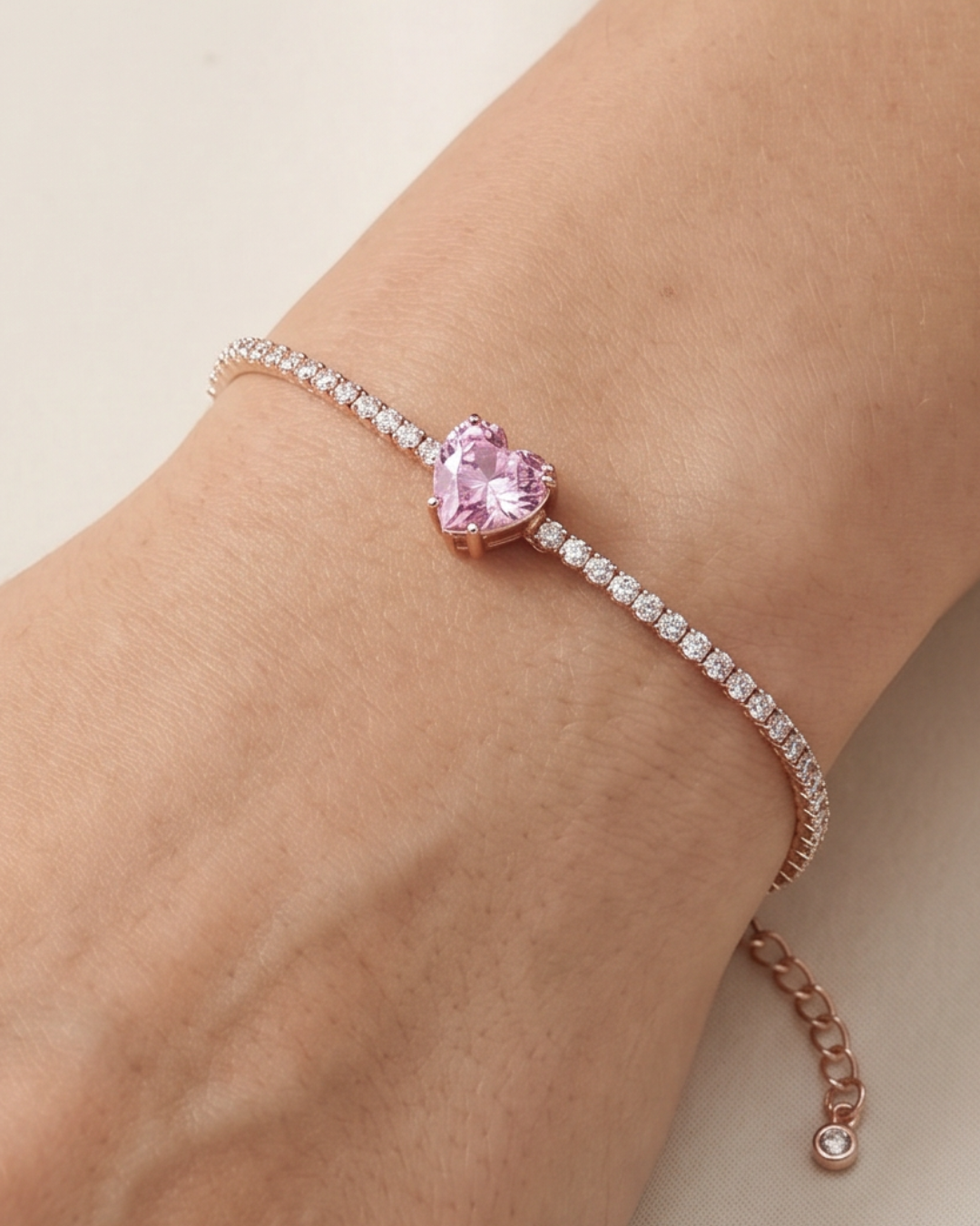Bracelet Tennis Cœur Rose en argent 925 doré a l'or rose 18 carats, composé d’une rivière de zirconiums blancs et orné d’un zirconium rose central en forme de cœur.