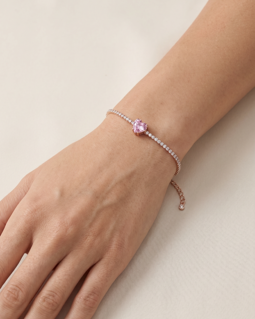 Bracelet Tennis Cœur Rose en argent 925 doré a l'or rose 18 carats, composé d’une rivière de zirconiums blancs et orné d’un zirconium rose central en forme de cœur.