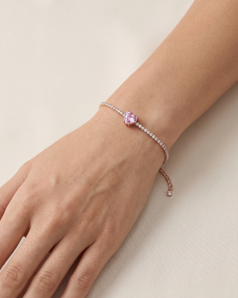 Bracelet Tennis Cœur Rose en argent 925 doré a l'or rose 18 carats, composé d’une rivière de zirconiums blancs et orné d’un zirconium rose central en forme de cœur.
