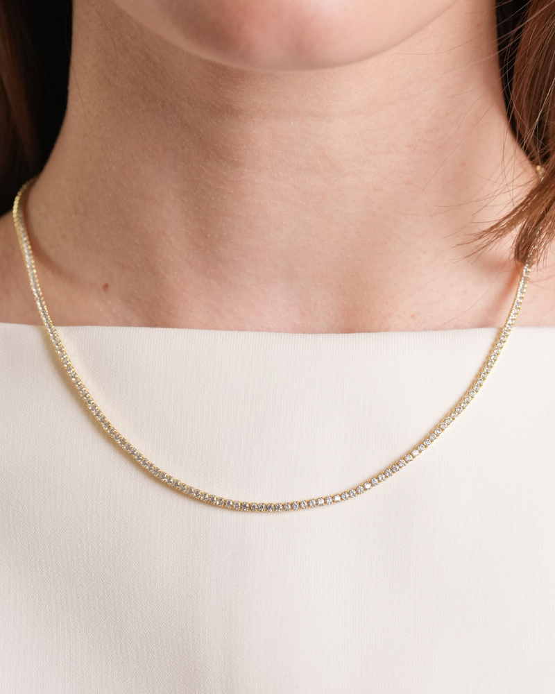 Collier Tennis Intemporel – Doré en argent 925 doré à l’or 18 carats, ligne continue de pierres délicatement serties pour un éclat uniforme et raffiné, finition lumineuse résistante à l’oxydation, fermoir sécurisé, conçu pour sublimer le décolleté.