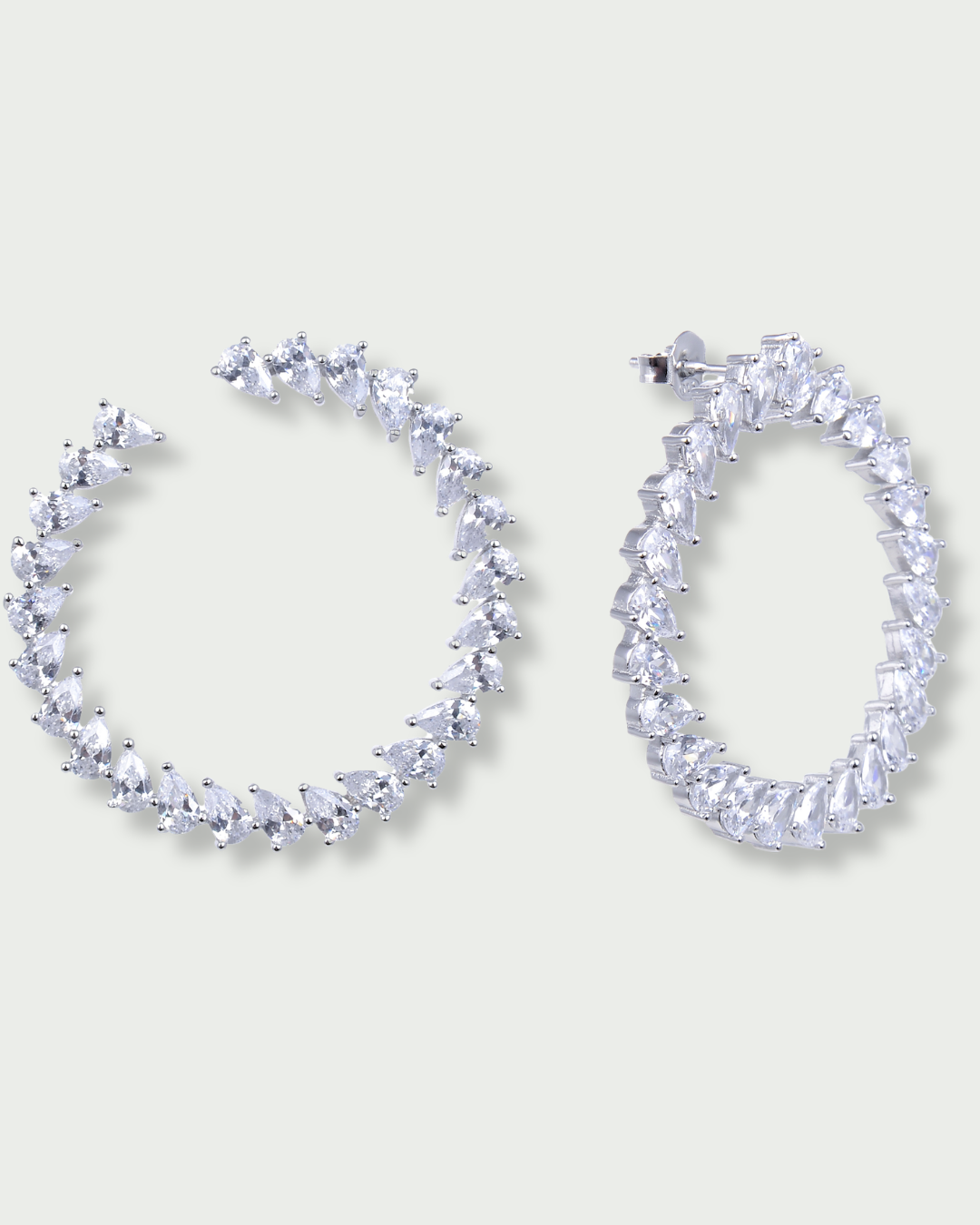 Boucles d’oreilles « Créoles Éclat ‑ Blanc » en argent 925 rhodié, créoles plates revisitées composées d’un délicat assemblage de mini‑zirconiums taille poire, finition polie brillante. 
