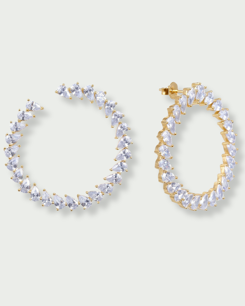 Boucles d’oreilles « Créoles Éclat ‑ Blanc » en argent 925 rhodié, créoles plates revisitées composées d’un délicat assemblage de mini‑zirconiums taille poire, finition polie brillante. 
