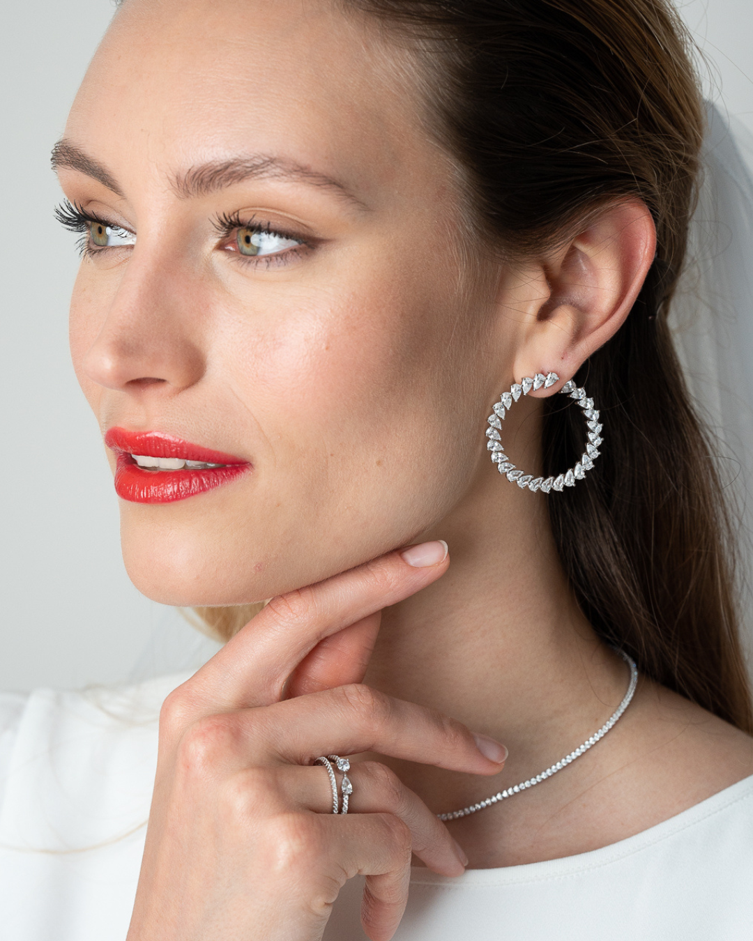 Boucles d’oreilles « Créoles Éclat ‑ Blanc » en argent 925 rhodié, créoles plates revisitées composées d’un délicat assemblage de mini‑zirconiums taille poire, finition polie brillante. 
