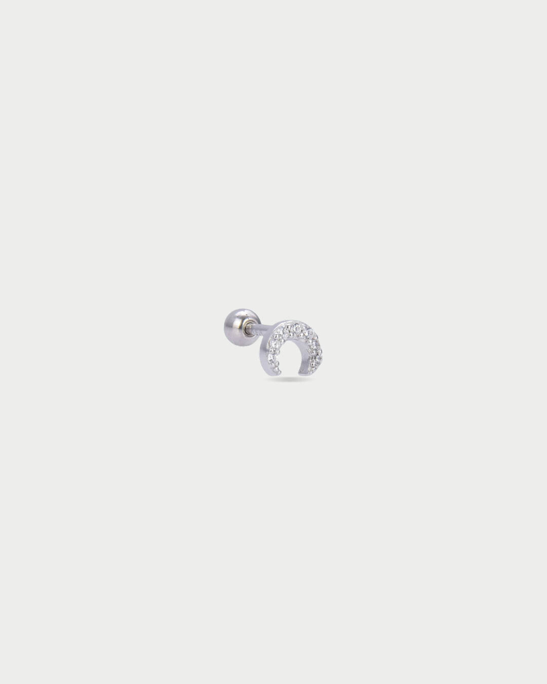 Piercing d’oreille en argent 925 millièmes rhodié, à la teinte blanche lumineuse, orné d’une petite lune délicatement pavée de zircons blancs. Sa silhouette céleste, fine et lumineuse, capte subtilement la lumière et illumine le lobe avec élégance