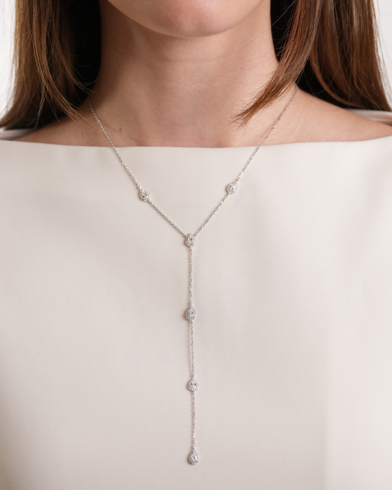 Ce sautoir délicat en argent 925 rhodié joue la carte de l’élégance aérienne. Les zircons blancs taille poire, sertis façon halo, s’enchaînent le long d’une chaîne fine et légère, créant une silhouette en cascade pleine de grâce.
