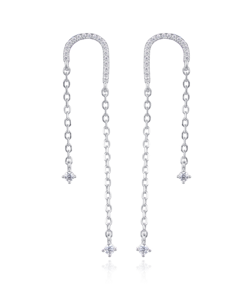 Boucles asymétriques en argent 925 rhodié, arc pavé de zirconiums et fines chaînes terminées par des pendants en pierres blanches.