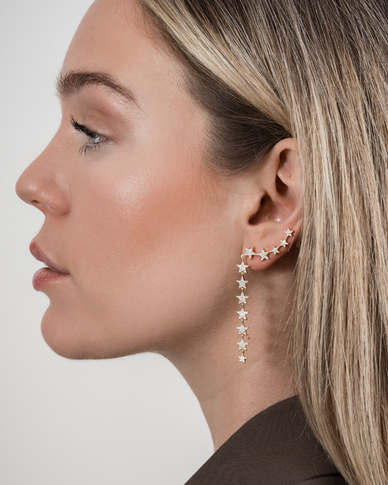 Boucles d’oreilles pendantes asymétriques forme étoile en argent 925 millièmes doré à l’or 18 carats, entièrement pavées de zirconiums lumineux. Design délicatement asymétrique apportant modernité et éclat, avec une silhouette étoile scintillante prolongée en pendantes. Longueur 4 cm, fermoir poussette avec tige, finition polie brillante.