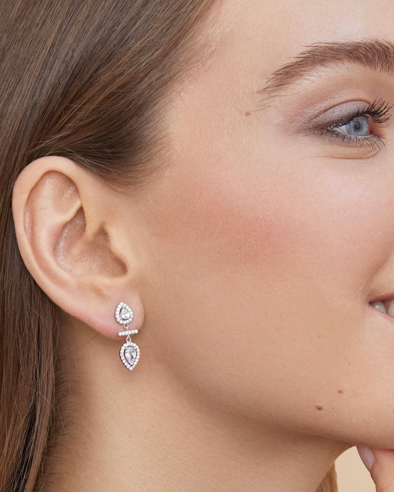 Boucles d’oreilles « Opposite Infini Poire » en argent 925 doré à l’or jaune 18 carats, deux zircons blancs taille poire montés en symétrie miroir séparés par une petite barre sertie, finition polie brillante.