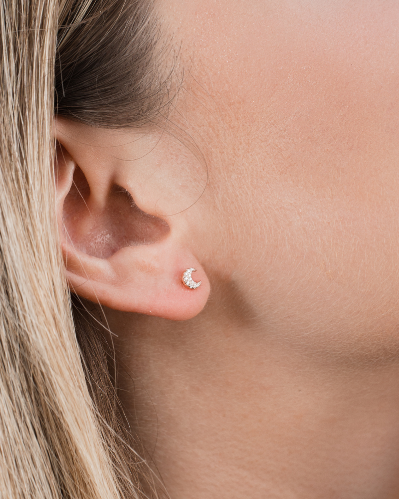 Boucles d’oreilles puces en argent 925 millièmes doré à l’or rose 18 carats, à la teinte chaude et lumineuse, délicatement pavées de zircons blancs. Leur silhouette en forme de lune, fine et céleste, capte subtilement la lumière et illumine le lobe avec douceur.